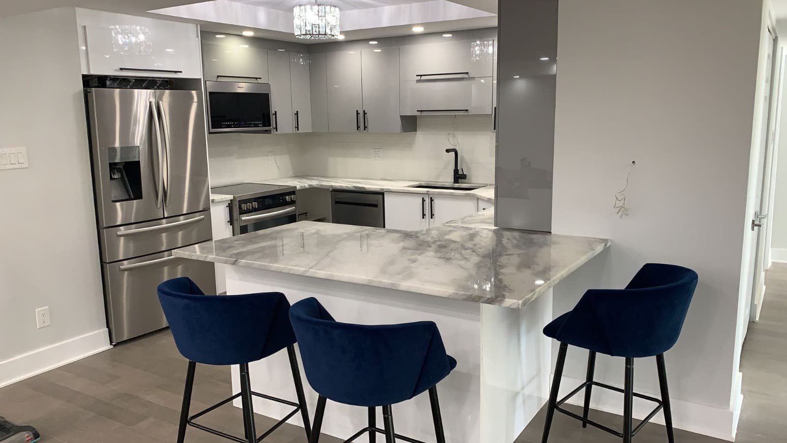 Gloss grey U-shape kitchen with grey quartz and navy stools