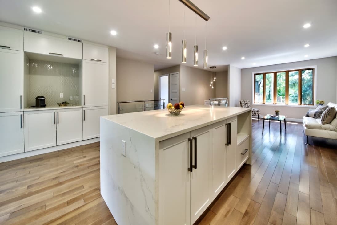 Cuisine blanche avec îlot en quartz calacatta et suspensions cylindriques