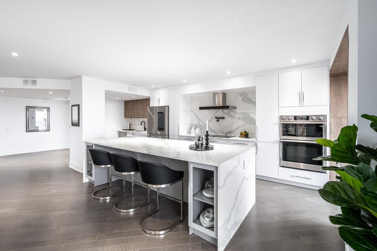 Grande cuisine blanche avec îlot en quartz calacatta et tabourets de bar