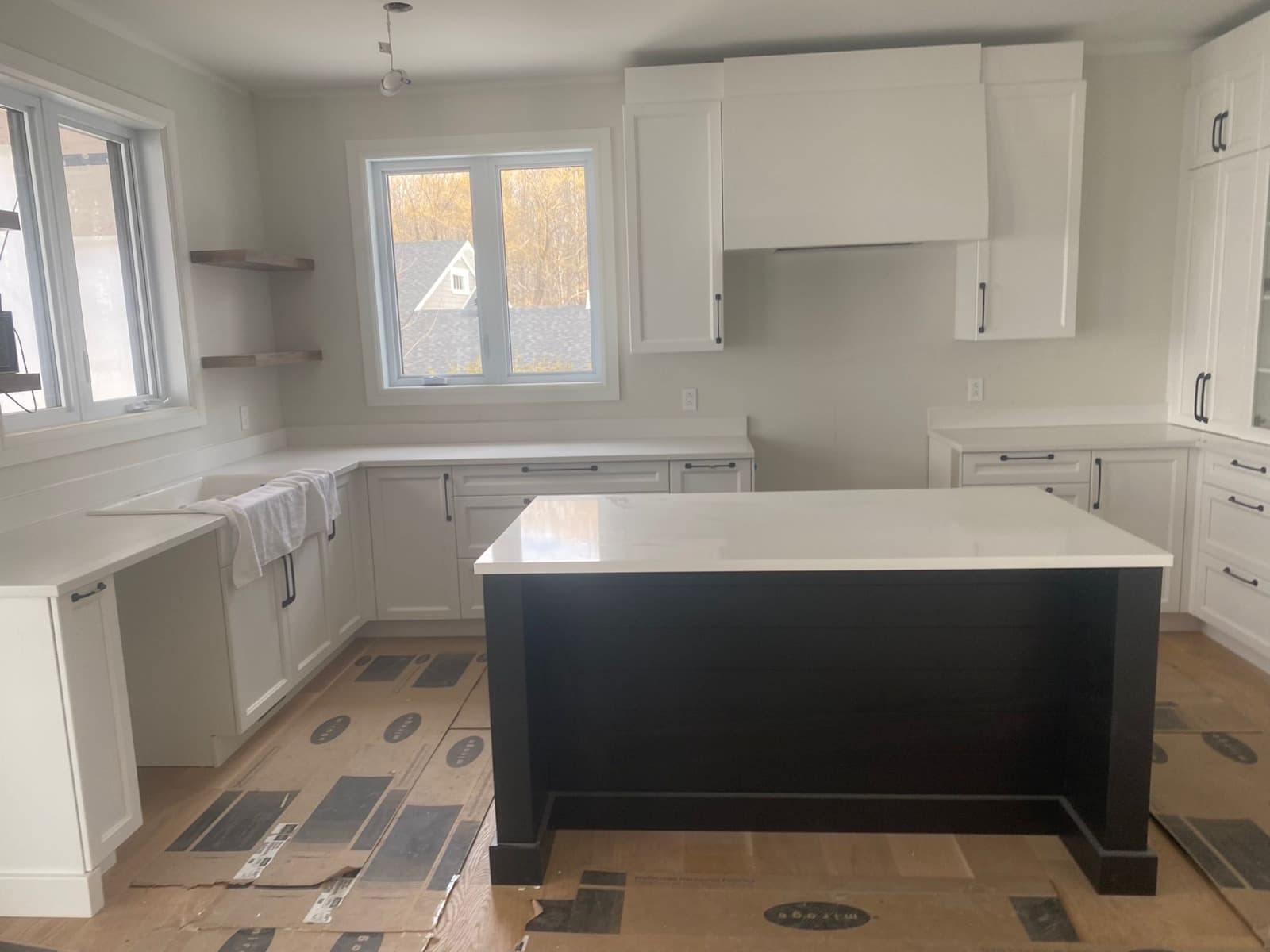Cuisine shaker blanche avec îlot foncé et tablettes ouvertes
